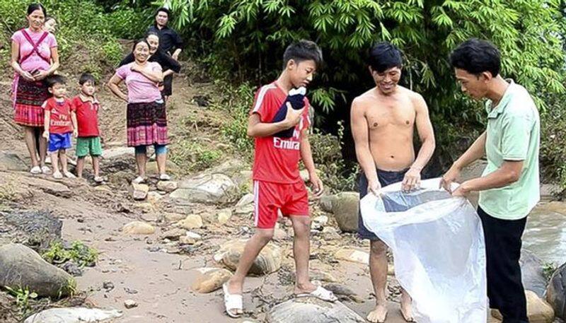 Children travel in plastic bags across flooded river so they can go to school