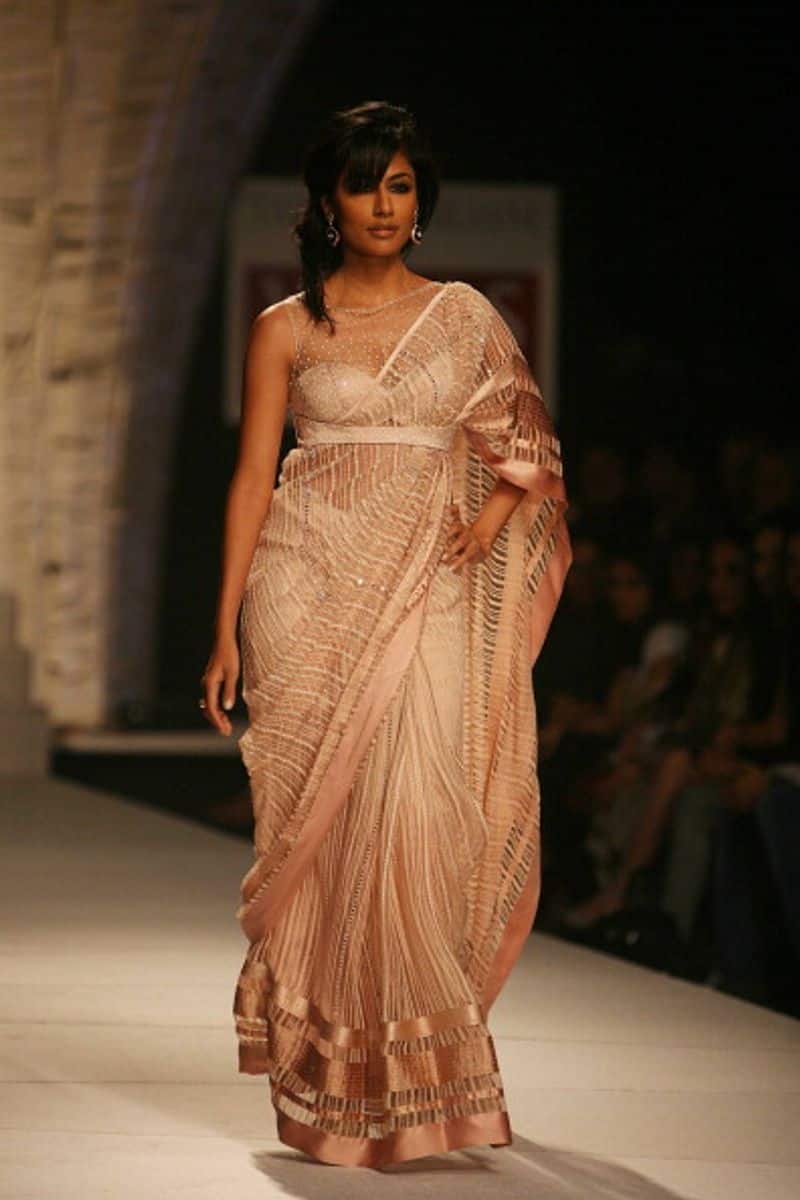 Pair a sheer sequinned sari with a cutout blouse and place the pallu through the cutout just like this Tarun Tahiliani design.