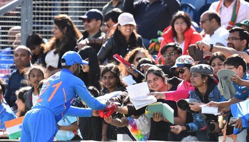 Dinesh Karthik signs autographs for fans.