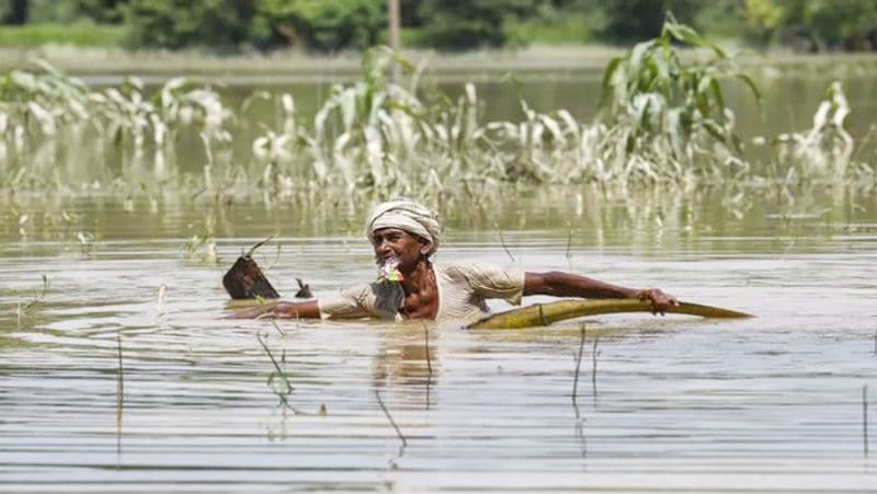 बिहार के मुजफ्फरपुर जिले में भारी बारिश के बाद एक निवासी बाढ़ के पानी से बाहर निकलने की कोशिश करता हुआ।