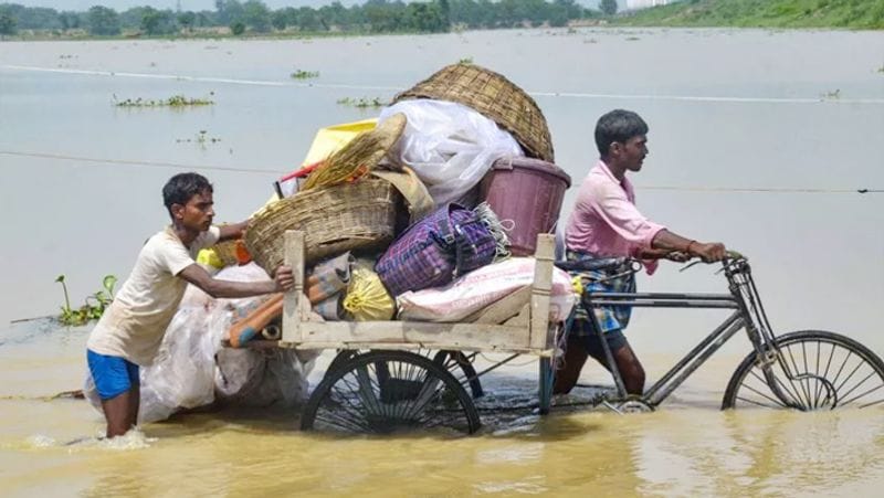 बाढ़ प्रभावित ग्रामीण अपने सामान को मुज़फ़्फ़रपुर जिले के मिथन शरई सुरक्षित स्थान पर पहुंचाते हुए।