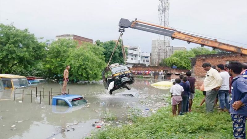 मिर्जापुर जिले में बाढ़ग्रस्त क्षेत्र से एक क्रेन ऑटोरिक्शा को बाहर निकालती हुई।