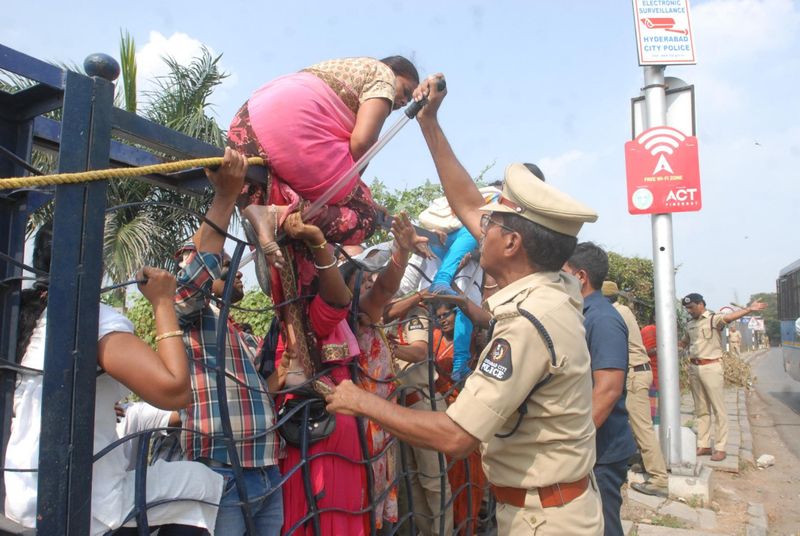 బారికేడ్లను దూకేందుకు ప్రయత్నిస్తున్న మహిళా కార్మికులను అడ్డుకుంటున్న పోలీసులు