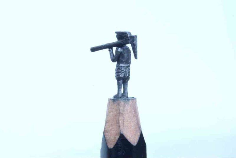 artist carving miniature sculptures on pencil tips