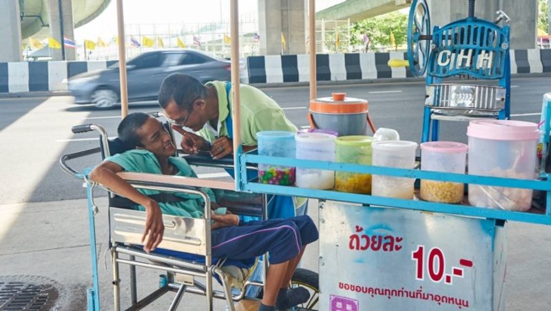 Old uncle sells icecream to support disabled son walking in heatwave at Bangkok