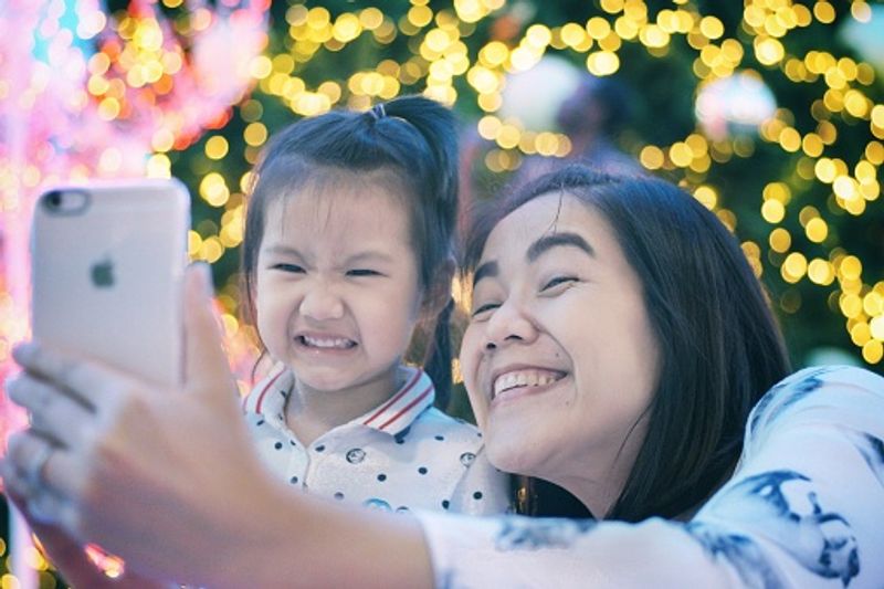 Daughters teach the mothers the selfie trick with the Christmas tree