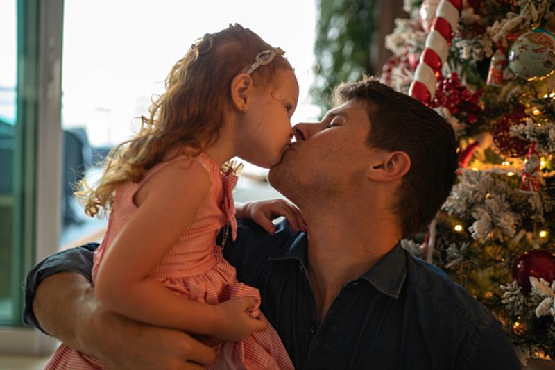 Father has his special moments with cute daughter in front of the Christmas three
