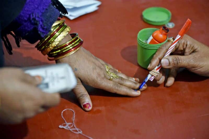 An electoral staff marks ink to a female voter after casting her vote at a polling booth for the Delhi Legislative Assembly elections, at Shaheen Bagh, in New Delhi on Saturday.