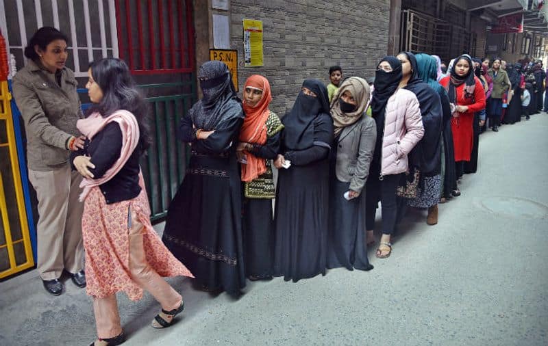 Female voters stand in a queue to cast their votes at a polling booth during the Delhi Legislative Assembly elections, at Shaheen Bagh, in New Delhi on February 8, 2020.
