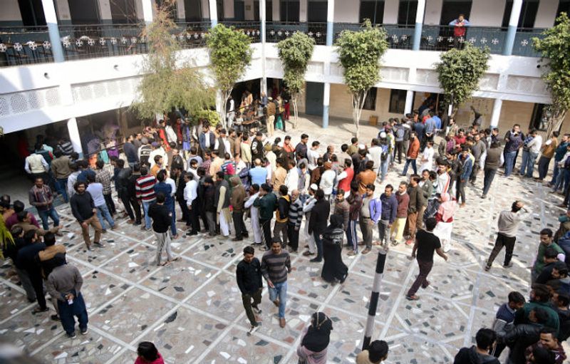 Voters stand in a queue to cast their votes at a polling booth during the Delhi Legislative Assembly elections, at Shaheen Bagh, in New Delhi on February 8, 2020.