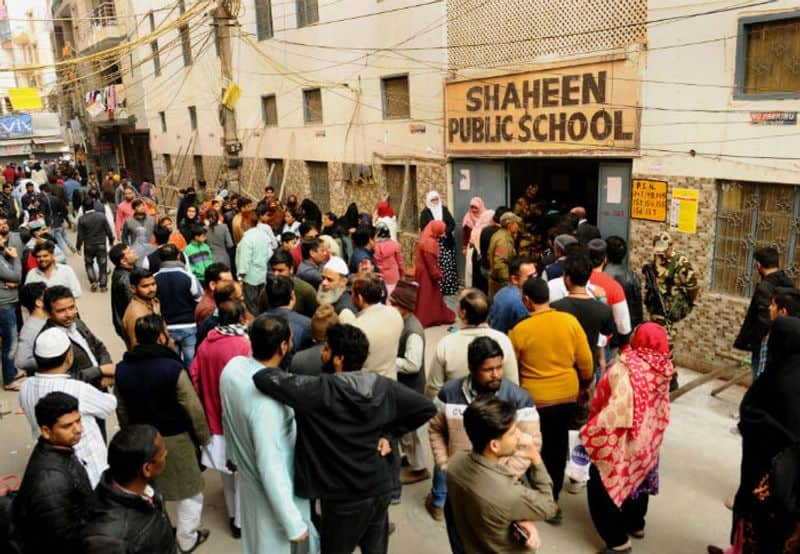 People stand in queue to cast their votes at a polling station at Shaheen Public School near the protest site for the protest against the Citizenship Amendment Act (CAA) and National Register of Citizens (NRC), in Shaheen Bagh area during Delhi State Assembly elections in New Delhi.