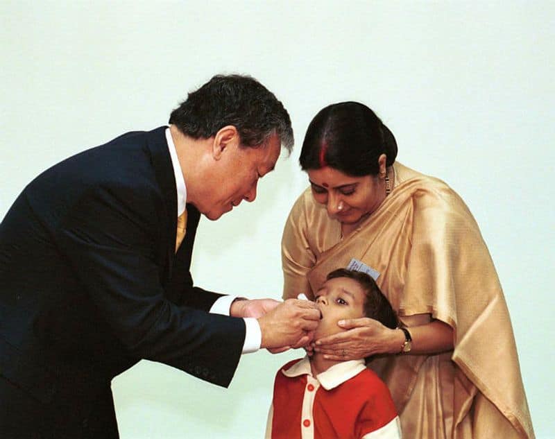 The Indian health minister Sushma Swaraj (R), and the director general of the World Health Organization, Dr. Jong-wook Lee (L), give a dose of oral polio vaccine to a boy on November 11, 2003. (Photo by Pallava BaglaCorbis via Getty Images)