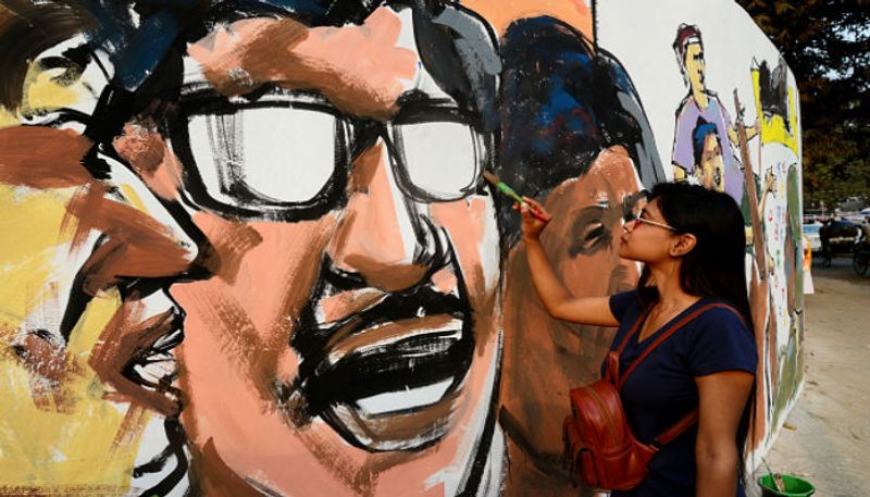 ঢাকায় শহিদ মিনারের সামনে এক তরুণী ভাষা-দিবস উপলক্ষে দেওয়াল চিত্র অঙ্কনে ব্যস্ত।