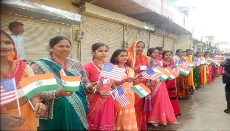 सड़कों के किनारे अमेरिका और भारत के ध्वज के साथ इस तरह खड़ी महिलाएं