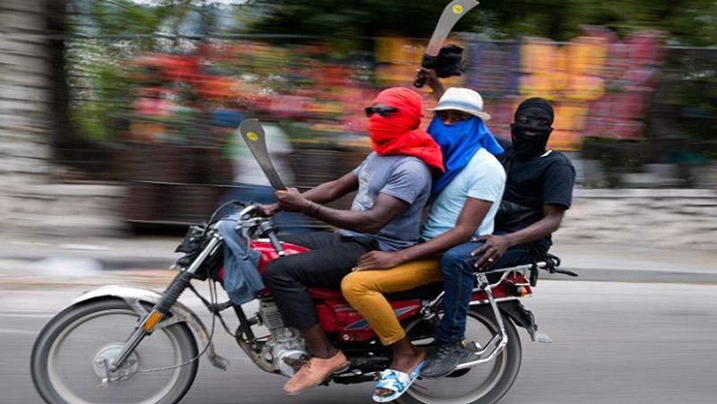 हिंसाग्रस्त हैती की राजधानी की एक सड़क से बाइक पर सवार युवक गुजरते हुए। पत्थरबाजी और आगजनी के कारण लोगों में डर फैल गया।