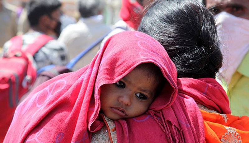 मासूम बच्चे को कांधे पर उठाए घर की ओर जाती एक महिला।