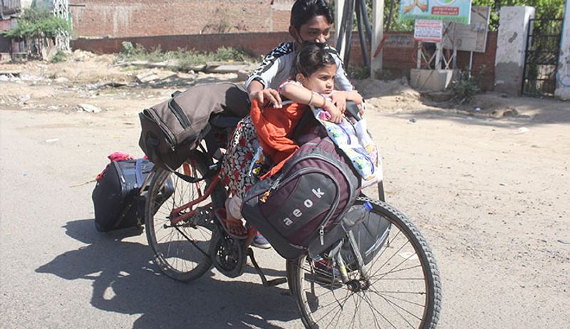 पापा हम कहां जा रहे हैं? साइकिल पर मायूस बैठी यह बच्ची शायद यही पूछ रही होगी।