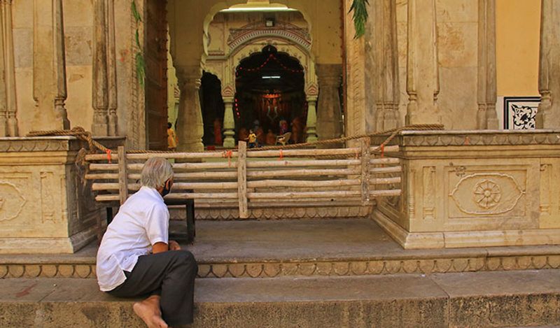 एक मंदिर के बाहर बैठा शख्स ईश्वर से सबकुछ जल्द बेहतर होने की कामना करता हुआ।