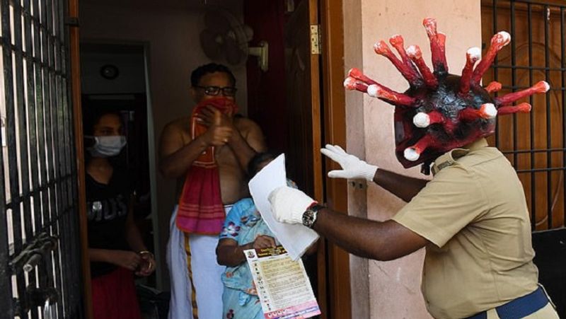 चेन्नई में एक पुलिसकर्मी कोरोनावायरस जैसा हेल्मेट पहने एक घर में जाकर इस वायरस से बचाव के उपायों के बारे में समझा रहा है।