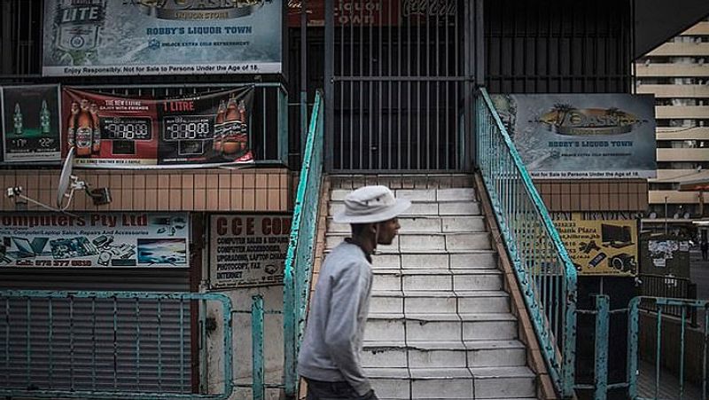 जोहान्सबर्ग में शराब की एक बंद दुकान के पास से गुजरता शख्स। यह तस्वीर 17 अप्रैल की है। 