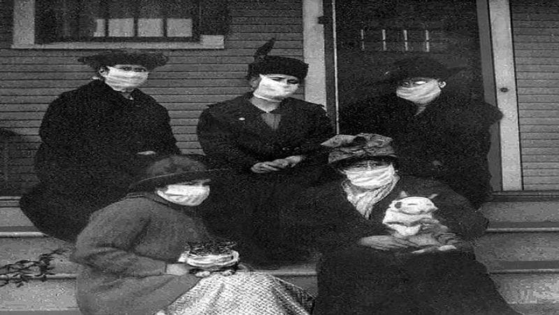 1918 में अमेरिका में फैली स्पेनिस फ्लू की महामारी के दौरान अपने घर के बाहर मास्क लगा कर बैठी कुछ महिलाएं। दो महिलाओं ने अपने पेट्स को भी मास्क पहना कर उन्हें गोद में ले रखा है। 
