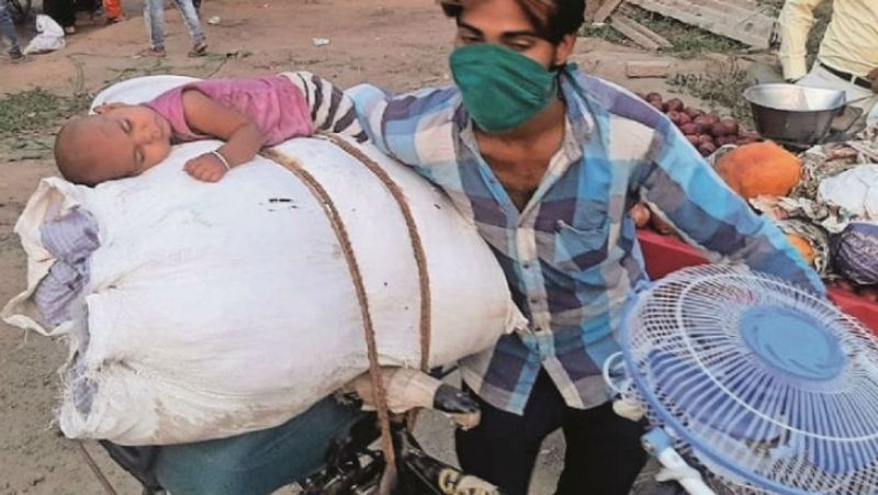 कल तक मेहनत करके सुकून की दो वक्त की रोटी कमाकर अपने बच्चों का पेट पाल रहे थे। अब यह मजदूर हालात और किस्मत के बेचारे बन गए हैं। वह अब बेबस और मायूस हैं, आंखों में सपने सजोए चिल्लचिलाती धूप में अपने घर जाने के लिए सपर पर निकल पड़े हैं। तस्वीर में आप साफ तौर पर देख सकते हैं किस तरह एक मजबूर बाप अपने मासूम बच्चे को तपती दुपहरी में साइकिल पर इस तरह सवार कर ले जा रहा है। देखिए मासम को तीखी धूप में ही सो गया, उसको छांव की जरुरूत नहीं पड़ी।