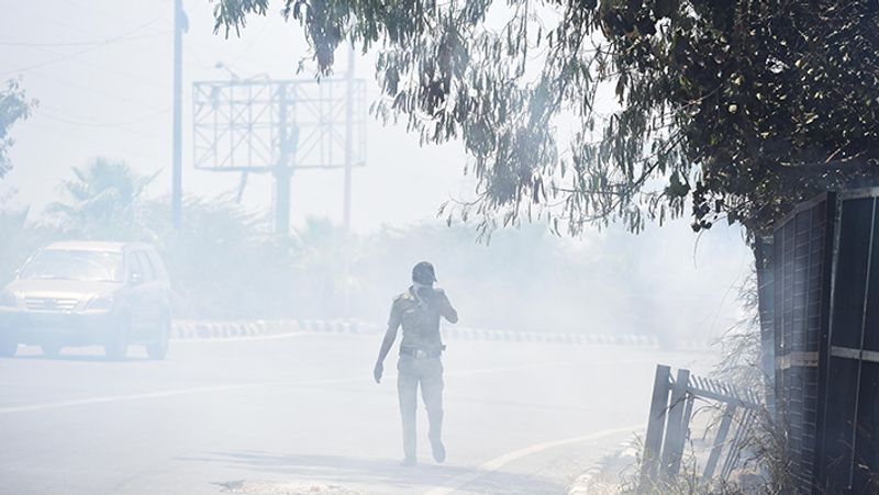 नई दिल्ली के लक्ष्मी नगर में झाड़ियों में आग लगने पर उसे बुझाने के लिए जाता पुलिसवाला।