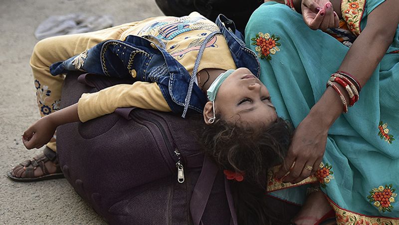 यह तस्वीर नोएडा की है। गाड़ी के इंतजार में मां के साथ बैठी बच्ची थककर ऐसे लगेज पर ही सो गई।