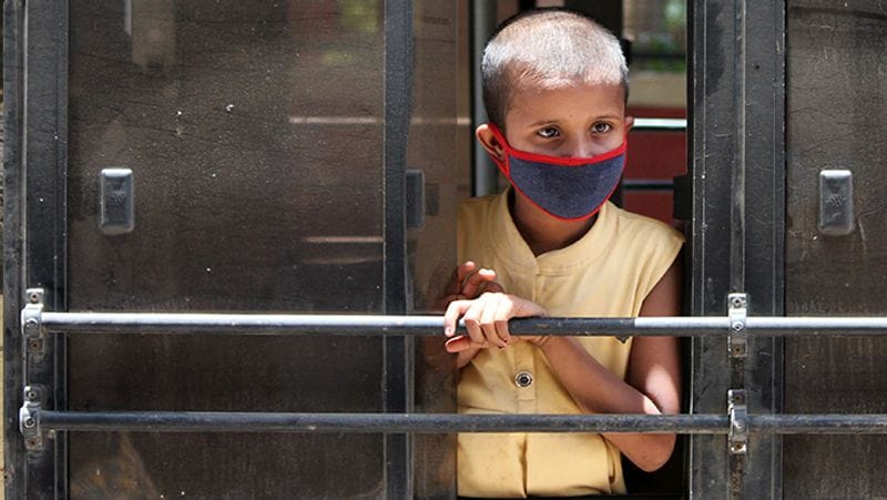अपने घर के लिए निकल प्रवासी मजदूर का बच्चा बस की खिड़की से झांकता हुआ। उसके चेहरे पर कहीं कोई डर नहीं दिखा।