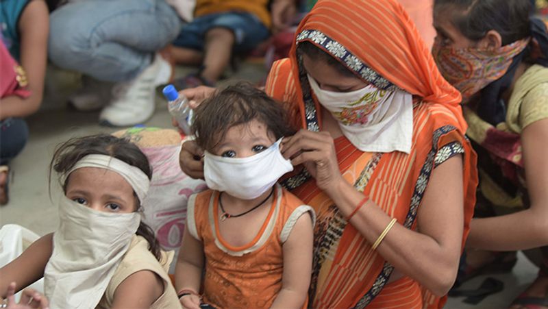 कोरोना संक्रमण से बचने के लिए बस यही समझदारी की जरूरत है। एक मां अपने मासूम बच्चे को मास्क लगाते हुए।