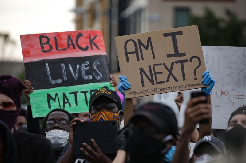 People hold banners reading "Black Lives Matter-Am I Next", as crowds gather to protest after the death of George Floyd in Washington DC United States on May 29.