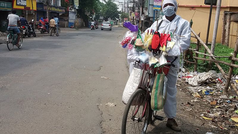 कोलकाता में साइकिल पर पीपीई किट पहनकर मॉस्क बेचने निकला एक शख्स।