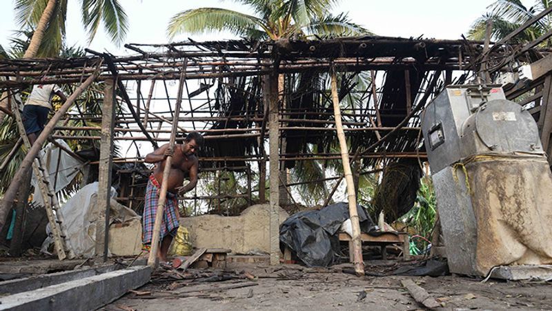तूफान से बर्बाद हुए अपने घर को फिर से दुरुस्त करता शख्स।