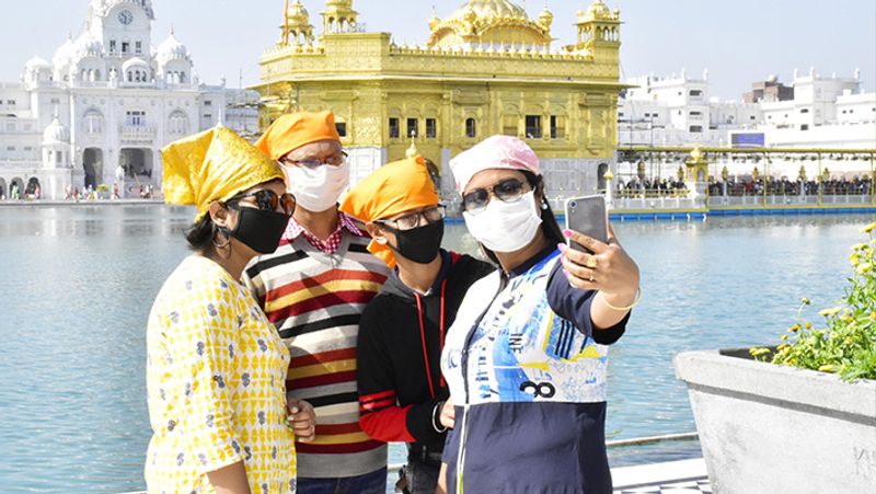 अमृतसर स्थित स्वर्ण मंदिर के बाहर सेल्फी लेता एक परिवार।