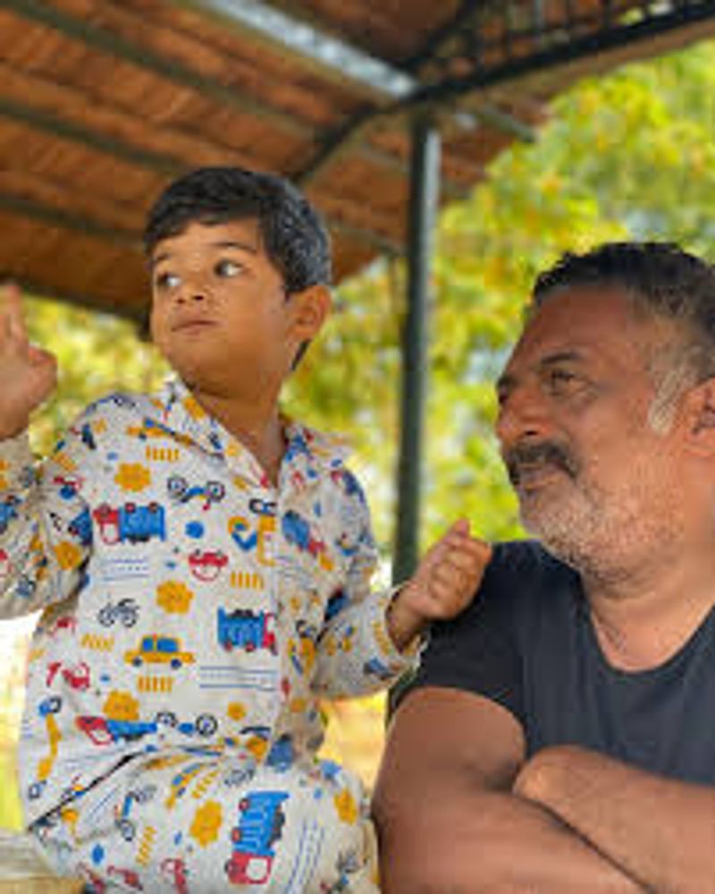 பிரகாஷ்ராஜ் தன் செல்ல குழந்தையுடன் எதையோ பார்த்து ரசித்து கொண்டு இருக்கிறார் 
