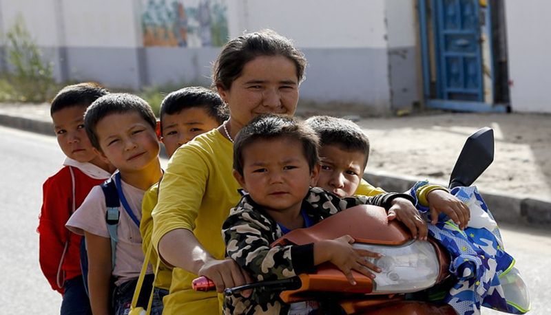 20 सितंबर, 2018 को फाइल फोटो में उइगर महिला और बच्चे पश्चिमी चीन के झिंजियांग क्षेत्र के होटन के यूनिटी न्यू विलेज में स्कूल के बाद मोटर-ट्राइसाइकिल पर बैठते हुए। होटन और काशगर के उइगर क्षेत्रों में जन्म दर 2015 के बाद से 60% से अधिक है, ऐसा सरकार के आंकड़े बताते हैं।
