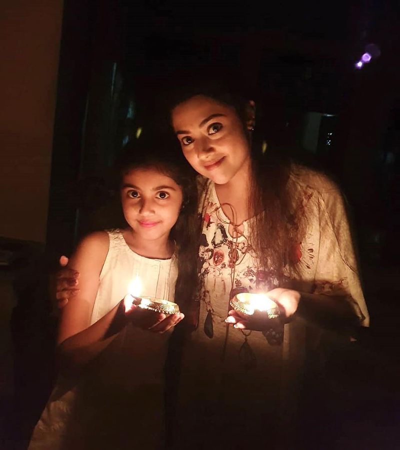 அம்மா குழந்தை விளக்கு கையில் வைத்து போஸ் கொடுக்கும் காட்சி 