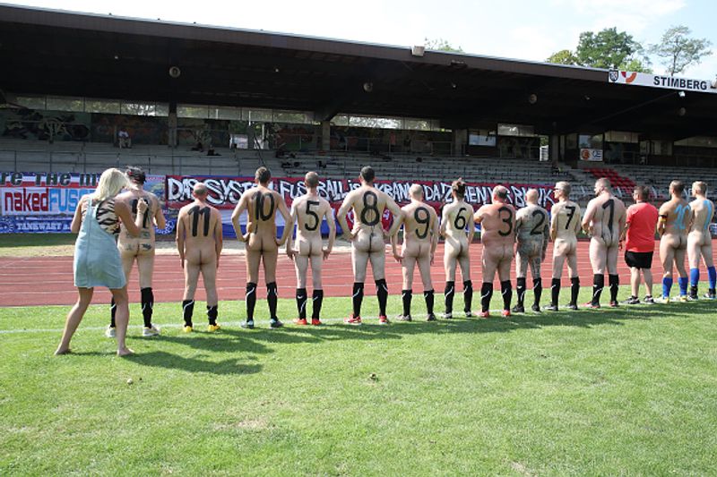 nude players play football in protest against corporate