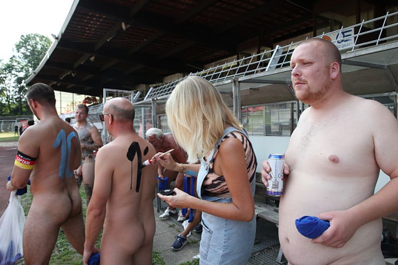 nude players play football in protest against corporate