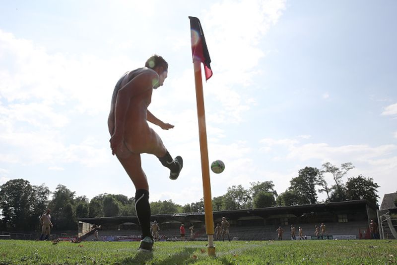 nude players play football in protest against corporate