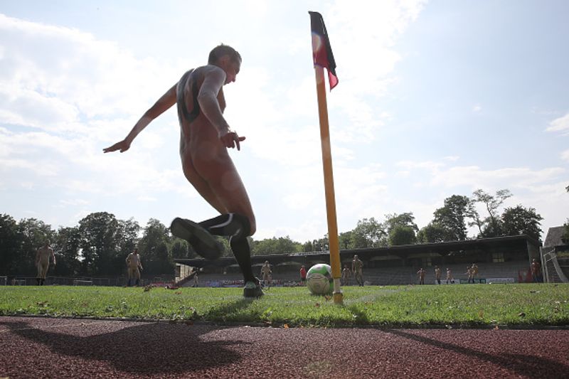 nude players play football in protest against corporate