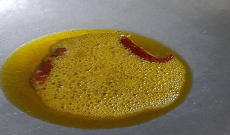 अब एक कड़ाही गर्म करें। इसमें तेल गर्म करें। अब इस तेल में सूखी लाल मिर्च डालें। 