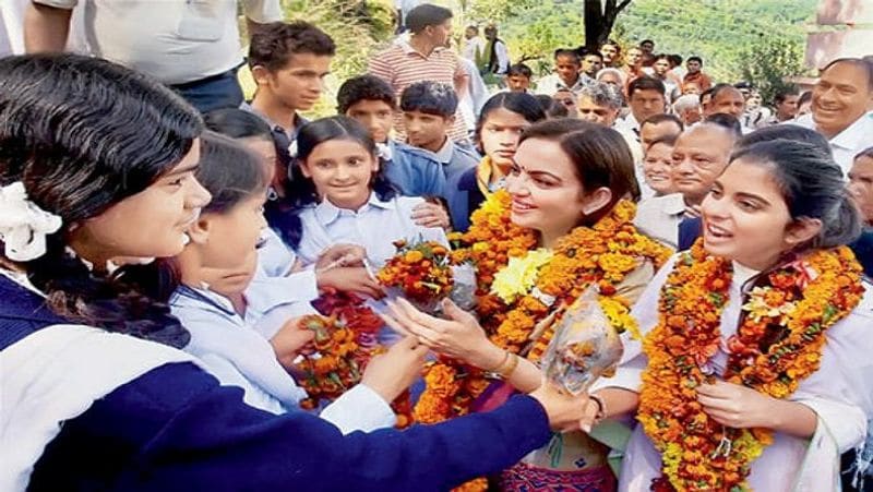 एक फंक्शन के दौरान स्कूली लड़कियां फूल माला पहना कर नीता अंबानी और ईशा अंबानी का स्वागत कर रही हैं। 