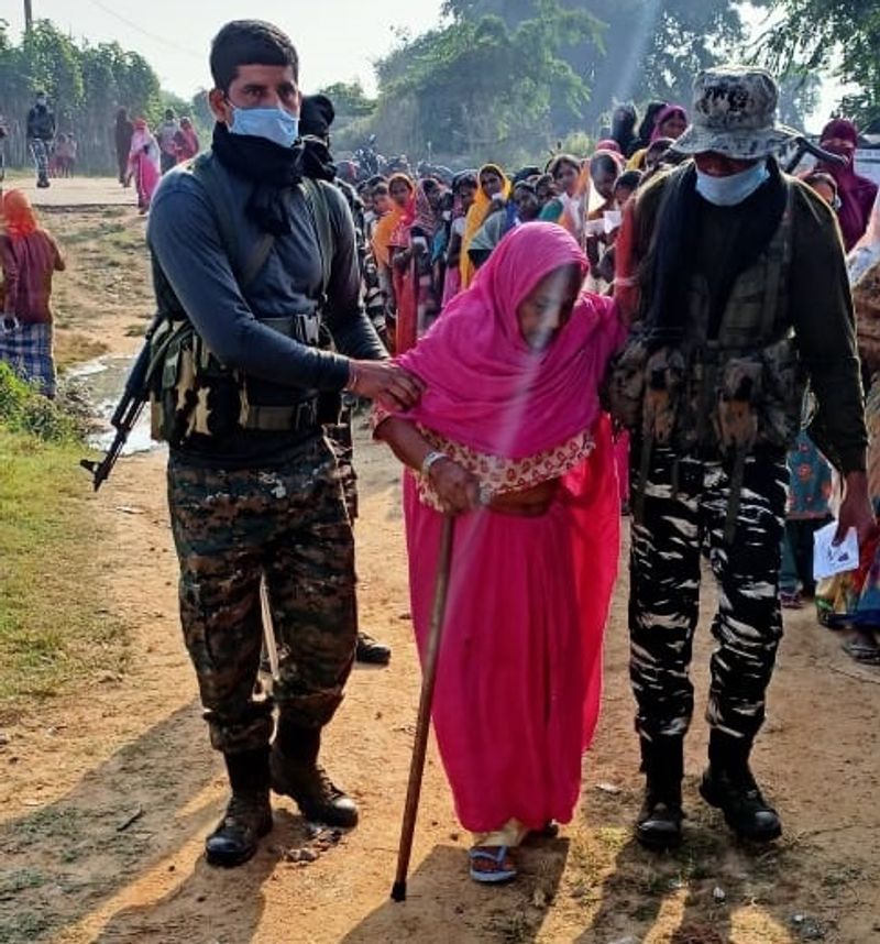 बिहार के एक मतदान केंद्र पर वृद्ध महिला मतदान की मदद करते सीआरपीएफ के जवान।
