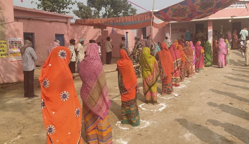 सोशल डिस्टेसिंग का पालन करते हुए मतदान के लिए कतार में खड़ी महिलाएं।
