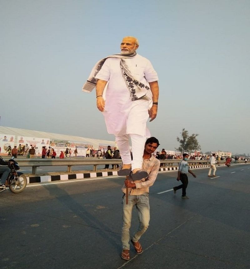 सड़क पर पीएम नरेंद्र मोदी की कट आउट लेकर जाता समर्थक। 