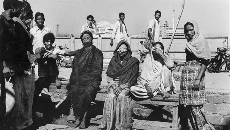 एक व्यक्ति, जिसका मैंने बयान दर्ज किया कि वह गैस लीकेज के समय अपनी मां-पत्नि और तीन बच्चों के साथ रात को भीड़ के साथ भागा था। लेकिन अंधाधुंध भागती हुई भीड़ में वह सड़क पर गिर गया। उसके ऊपर से भीड़ भागती रही। पैर बुरी तरह कुचल गया और वह बेहोश हो गया। उसका परिवार बिछड़ गया। जब उसको होश आया तब वह भारी बोझ के नीचे दबा था, जिससे निकलने की भरसक कोशिश करने पर उसने पाया कि वह लाशों के ढेर मे दबा था।
दरअसल, लाशों को औऱ मरीज़ों को अस्पताल पहुंचाने वालों ने उसे मुर्दा समझ कर अस्पताल के मरचुरी (मुर्दाघर) में जमा कर दिया था जहां लाशों के ढेर लगे थे और लगातार आने वाली लाशों का अम्बार उस पर लग गया था। उसका एक पैर टूट चुका था। फिर भी वह अपनी पूरी ताक़त इकट्ठी कर घिसटता हुआ गेट तक पहुंचा, जो बंद था। दरवाज़ा पीटने पर दरवाज़ा खोलने वाला व्यक्ति चीख़ मारता हुआ भाग गया। इसने चिल्लाने व पुकारने की कोशिश की और आख़िर फिर बेहोश हो गया।
जब पुन: होश आया तब वह अस्पताल के बेड पर था। उसका एक पैर ऑपरेशन से काटा जा चुका था। अब अस्पताल से छुट्टी करा के वह अपने परिवार को तलाश रहा था। मृतकों की सूची में उसकी मां को उसने ढूंढ लिया था लेकिन उसकी पत्नि और बच्चों का कुछ पता नहीं चला। वह जब घर से भागा था, तब घर खुला छूट गया था। जब वह वापिस घर गया, तो उसके घर का तमाम सामान चोरी हो चुका था। वह व्यक्ति रोता जाता था और खांसी से बेहाल हो रहा था।
सुबह 9 बजे से शाम तक पसीने-पसीने हम भीड़ से घिरे रहते। इस तरह के बयान कलमबंद करते रहते। लोग हमारे चारों तरफ़ खांसते और रोते रहते। उनकी लाल आंखों से पानी बहता रहता। कभी वेरीफ़िकेशन के लिए गैस प्रभावित बस्तियों में घूमते। धीरे-धीरे मेरी आंखें भी लाल रहने लगीं। उनसे पानी बहने लगा। खांसी भी धीरे-धीरे बढ़ती चली गई। हाथों पर चकत्ते से पड़ने लगे, जिनमें खुजली भी होती थी। अधिक बीमार हो जाने पर मुझे दो माह बाद अवकाश पर जाना पड़ा।
आगे देखें कुछ तस्वीरें...
