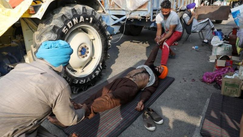 किसान अपने स्वास्थ्य का भी ध्यान रख रहे हैं। दो किसान अपने साथी के हाथ पैर खींचते हुए। 