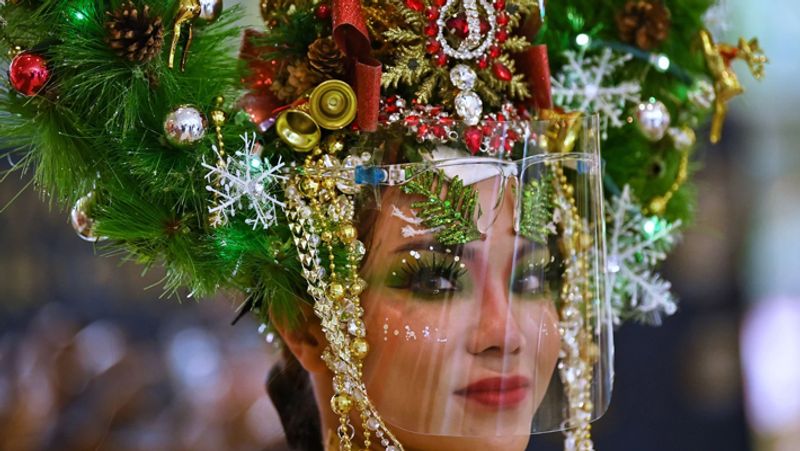 ग्रीस: ग्रीस में यह क्रिसमस हर साल की तरह नहीं है। सामान्य दिनों में सारे दिन बच्चों के गाने की आवाज सुनाई देती थी। यहां दशकों पुरानी परंपरा थी कि बच्चे घर घर जाते थे उन्हें वहां से छोटे गिफ्ट मिलते थे। लेकिन इस बार इस प्रथा पर रोक लगा दी गई है। बच्चों ने वीडियो बनाकर प्रधानमंत्री के लिए गाना गाकर इस परंपरा को पूरा किया। (फोटो- बैंकॉक में एक कार्यक्रम के दौरान क्रिसमस ट्री और फेसशील्ड पहने एक मॉडल।)