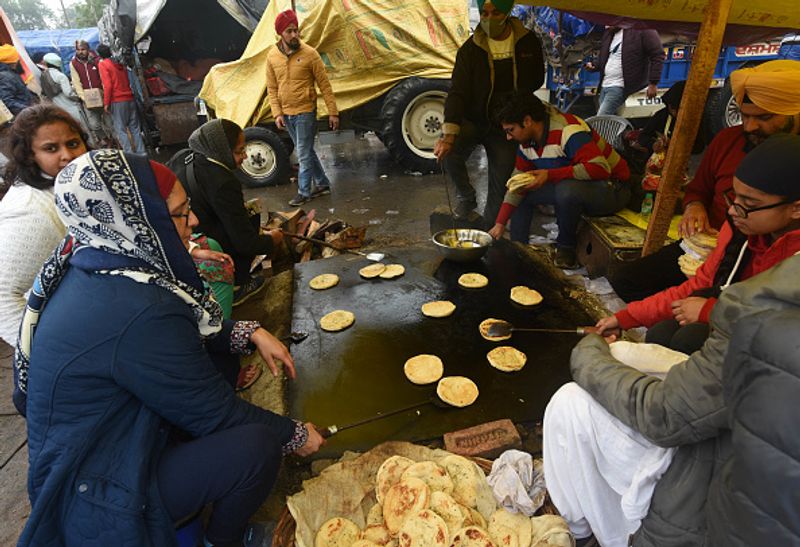 नए कृषि कानूनों के खिलाफ विरोध प्रदर्शन के दौरान सिंघू सीमा पर बारिश के दिन सामुदायिक रसोई में तैयार किया जा रहा भोजन। यहां पर लंगर के जरिए भी किसानों को खाना पहुंचाया जाता है।
